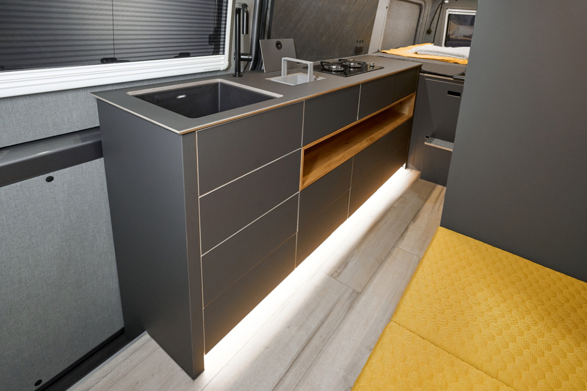 VanMe Camperausbau Elegant washbasin in matt black made from a mixture of minerals. Indirect lighting close to the floor in the offset of the furniture. 